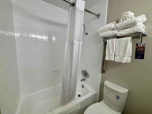 a bathroom with a toilet and a shower with towels at Baymont by Wyndham Keokuk in Keokuk