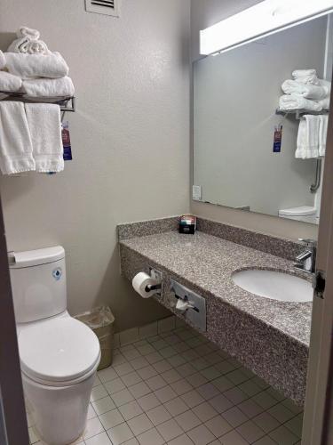 a bathroom with a toilet and a sink and a mirror at Baymont by Wyndham Keokuk in Keokuk