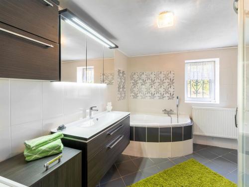 a bathroom with a tub and a sink and a bath tubermott at Lodge in Bohemia with Sauna and Bubble Bath in Kraslice