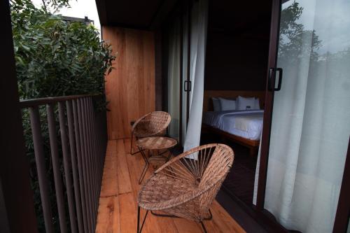 a balcony with two chairs and a bed on a porch at Casa de Agua in Tepoztlán