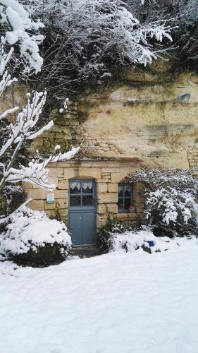 a stone building with a door in the snow at Troglo - gîte dans la pierre in Villaines-les-Rochers