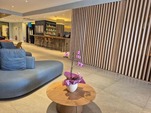 a living room with a couch and a table with a vase at Flat Aeroporto Congonhas (Apto 714) in Sao Paulo