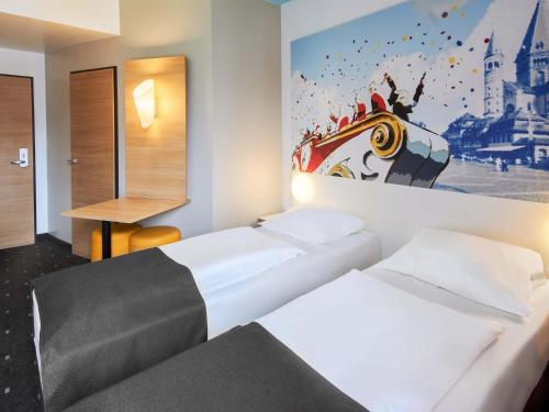 two beds in a hotel room with a painting on the wall at B&B Hotel Mainz-Hbf in Mainz