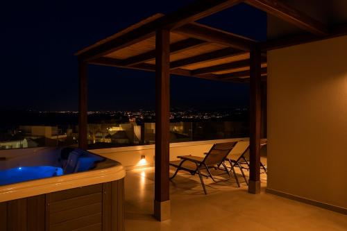 a balcony with a hot tub and chairs on a roof at See2sea Cozy Apartments in Kolymvari