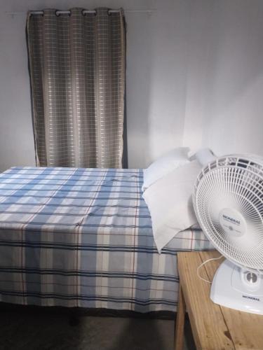 a bedroom with a bed with a fan on a table at Casa da Lika in Ilha de Boipeba