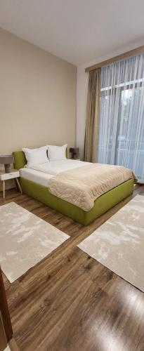 1 dormitorio con 1 cama y una ventana con alfombras en Green apartment Velingrad, en Velingrad
