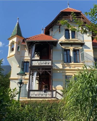 a large white house with a balcony on a hill at Villa Streintz in Millstatt