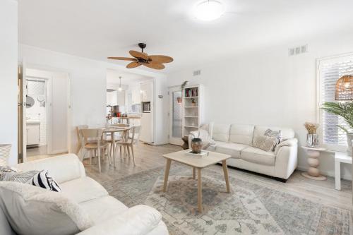 a living room with white furniture and a ceiling fan at Rockingham Beach Breeze 2BR Retreat in Rockingham