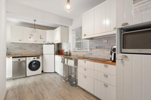 a kitchen with white cabinets and a washer and dryer at Rockingham Beach Breeze 2BR Retreat in Rockingham