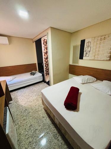 a bedroom with a large white bed with a red towel on it at Pousada Mãe Padroeira in Aparecida