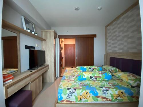 a bedroom with a bed with a colorful comforter at Grand Kamala Lagoon by 21 Room Netflix in Bekasi