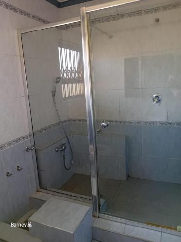 a shower with a glass door in a bathroom at M Palace Guest House in Kempton Park