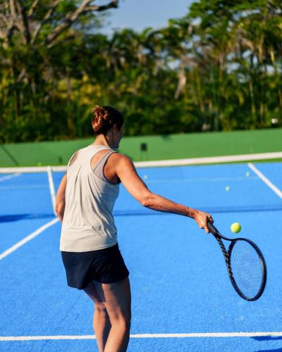 a woman holding a tennis racket on a tennis court at Zendaya Resort Beach Sport & Spa in Búzios