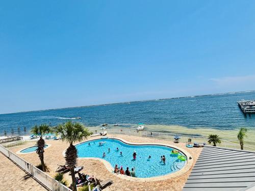 a swimming pool next to the ocean with people in it at Ocean Serenity in Pensacola