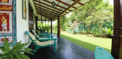 a porch with green tables and chairs and a garden at ayurvedamountainvilla in Nikawatawana