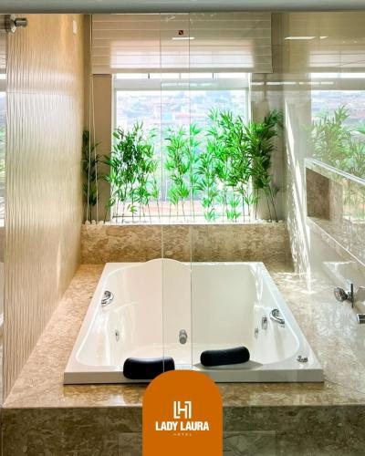 a bath tub in a bathroom with a large window at Lady Laura Hotel in Taquarituba