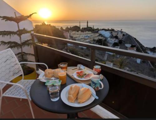 a table with plates of food on a balcony with the sunset at casa mariposa in Playa de Santiago