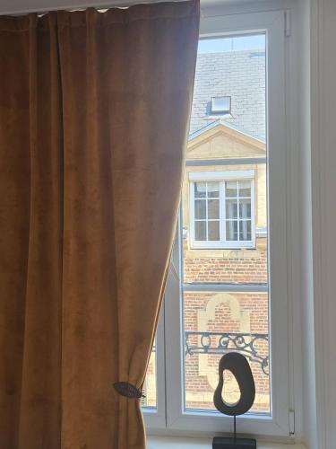 a window with a curtain and a chair in front of it at Suite et duplex avec terrasse en hyper centre in Charleville-Mézières