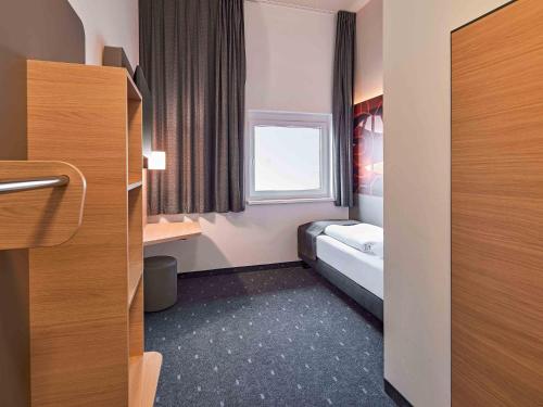 a small room with a bed and a window at B&B Hotel Hamm in Hamm