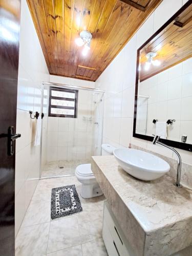 a bathroom with a sink and a toilet and a mirror at Charme nas montanhas com lareira in Campos do Jordão