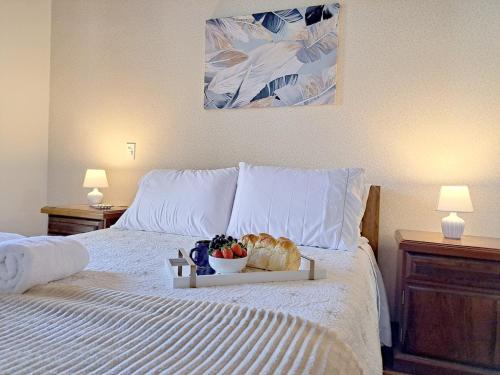 a tray of bread and a bowl of fruit on a bed at Charme nas montanhas com lareira in Campos do Jordão
