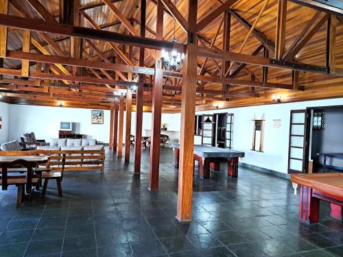 a large room with wooden beams and tables and benches at Charme nas montanhas com lareira in Campos do Jordão
