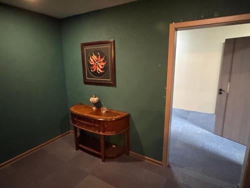 a green wall with a wooden table in a room at Summer hostel in Ulaanbaatar