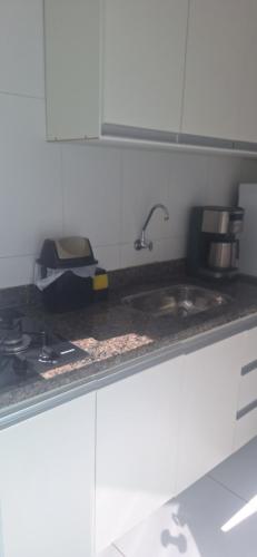 a kitchen counter with a sink and a stove at Loft Murano in Paulínia
