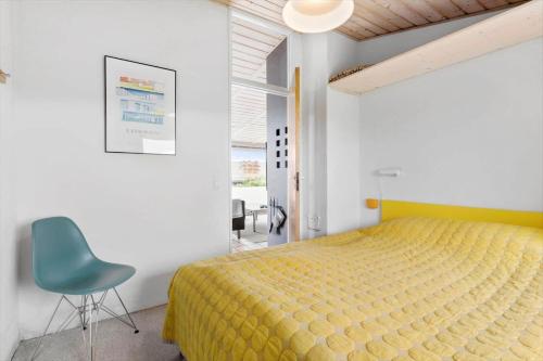 a bedroom with a yellow bed and a blue chair at LN1963-Hirtshals-Klynen-19 in Hirtshals