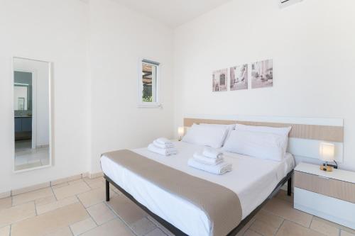 a white bedroom with a bed and a mirror at Rock'n'Trullo 4 bedroom privatepool by TripOstuni in Ostuni