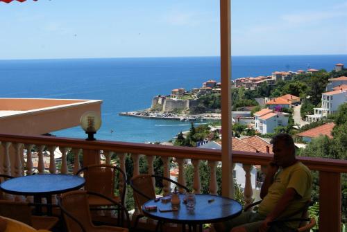 a man sitting on a balcony with a view of the ocean at Apartments Panorama Alaj in Ulcinj