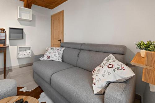 a living room with a gray couch with two pillows at Grand-St-Bernard, Liddes - 4 pers - cosy & rénové in Liddes