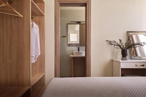 a bedroom with a bed and a mirror and a sink at Ilision Aqua - Exclusive Private Pool Suites in Argasi