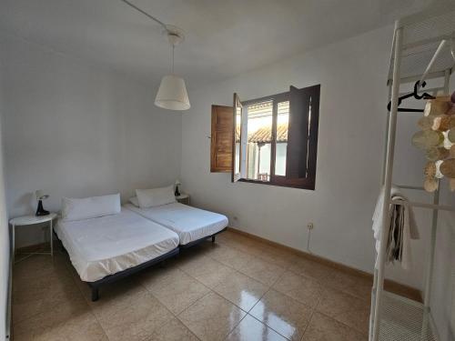 a white bedroom with a bed and a window at Casa Pino Teror in Teror