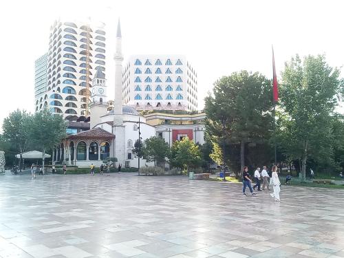 a group of people walking around a plaza with buildings at Ofellows - Tirana City Center in Tirana