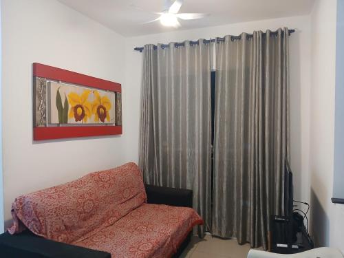 Una sala de estar con un sofá y una ventana. en Apartamento á 2 minutos da Praia, en Praia Grande