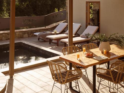 a patio with tables and chairs and a pond at Ilision Aqua - Exclusive Private Pool Suites in Argasi