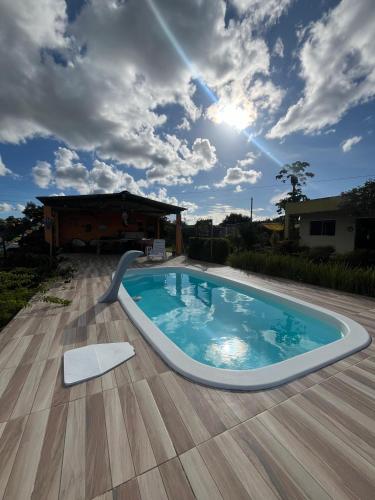 a swimming pool on a wooden deck with a cloudy sky at Chalés Aconchego da Serra in Sairé