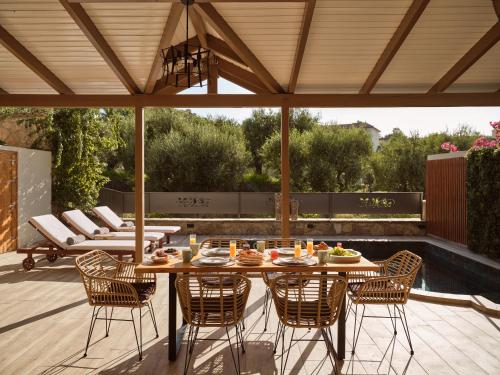 a wooden table and chairs on a patio with a roof at Ilision Aqua - Exclusive Private Pool Suites in Argasi