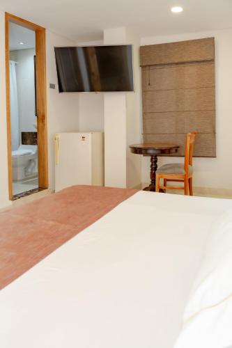 a bedroom with a bed and a table and a television at Hotel San Pedro del Fuerte in Medellín
