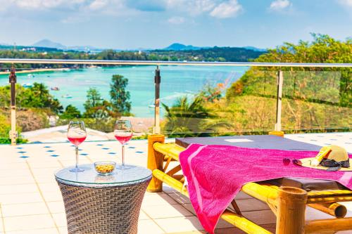two glasses of wine sitting on a table on a balcony at Phuket Arkadia Home in Nai Harn Beach