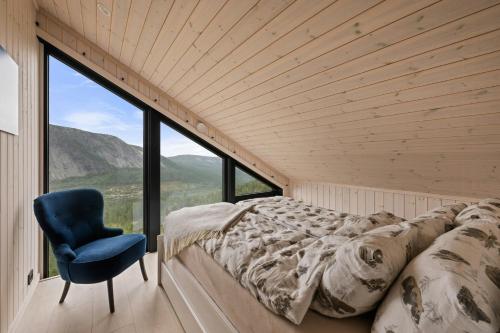 a bed and a chair in a room with a large window at Authentic Cabin Life With Løefjell View in Rysstad