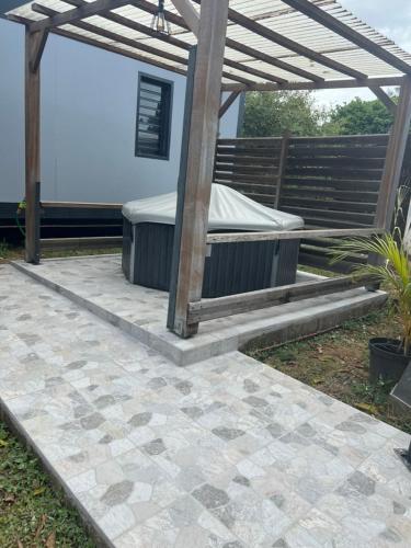 a patio with a bed under a wooden pergola at Résidence Morphée - chaleureux avec jacuzzi in Montjoly