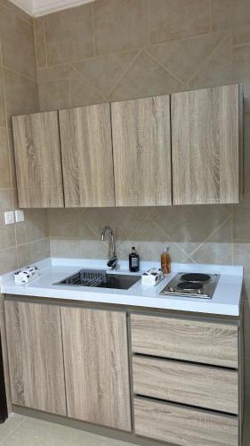 a kitchen with wooden cabinets and a sink at شقه بغرفه وصاله ومطبخ باثاث انيق in Buraydah