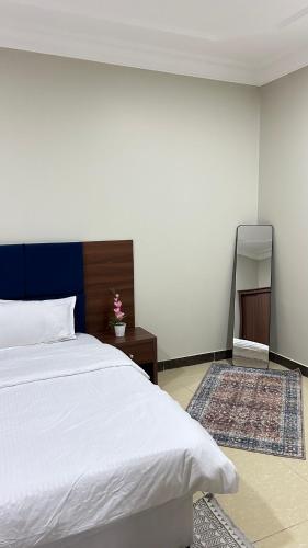 a bedroom with a white bed and a mirror at شقه بغرفه وصاله ومطبخ باثاث انيق in Buraydah