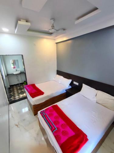 a room with two beds and a mirror at Rudra Guest House verul in Ellora