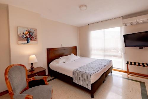 a bedroom with a bed and a television and a chair at Hotel San Pedro del Fuerte in Medellín