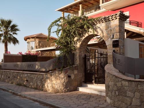 a building with a stone wall and a gate at Ilision Aqua - Exclusive Private Pool Suites in Argasi