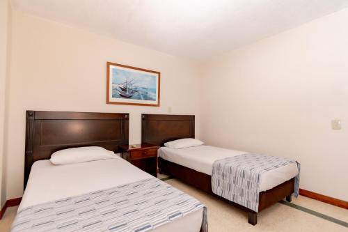 a bedroom with two beds and a picture on the wall at Hotel San Pedro del Fuerte in Medellín