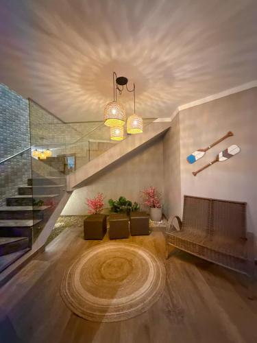 a living room with a couch and a staircase at Luxo Frente Mar em 7 Qtos com Ar sendo 4 suites para até 18 pessoas, 2 Jacuzzi Aquecidas, piscina, brinquedoteca, 5min de Castelhanos in Anchieta